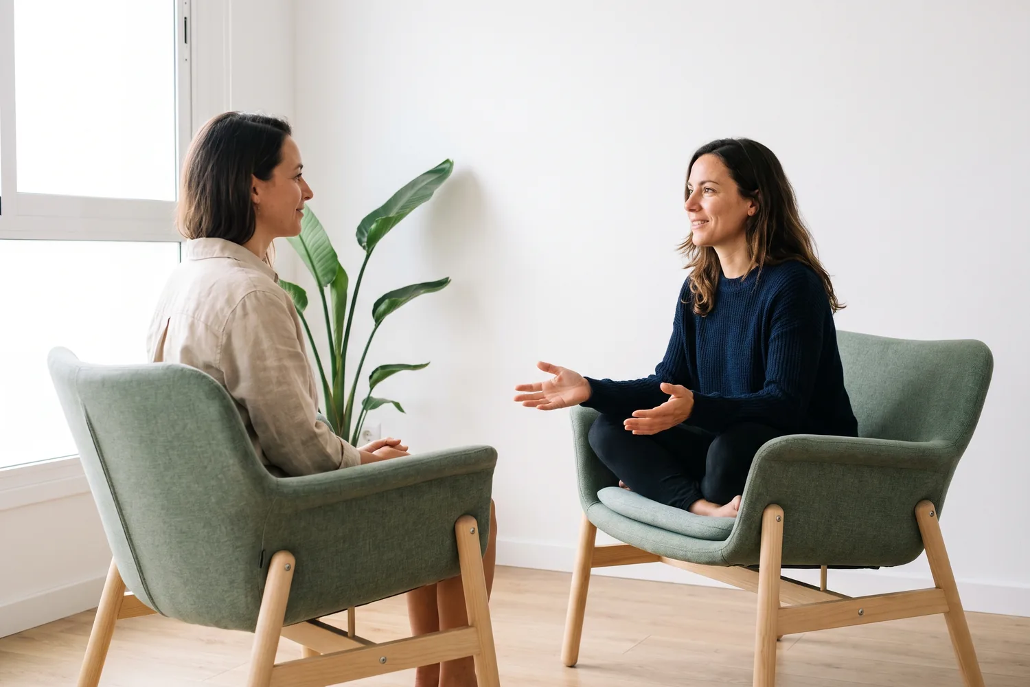 Dos personas sentadas frente a frente en una sesion de coaching personal: una habla con las manos abiertas y la otra escucha