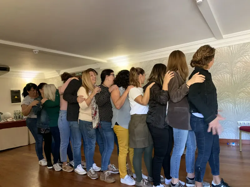 Grupo abrazado en fila durante una dinámica de taller